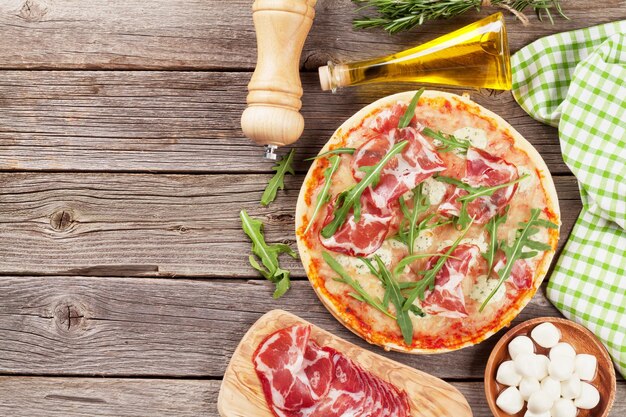 Pizza with prosciutto and mozzarella on wooden table