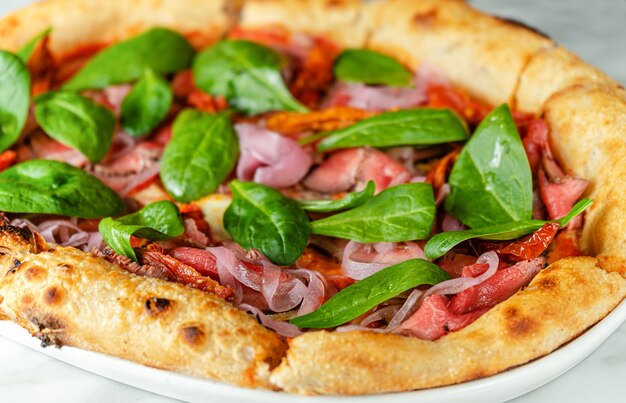 Pizza con roast beef, pomodori secchi, cipolla marinata e spinaci