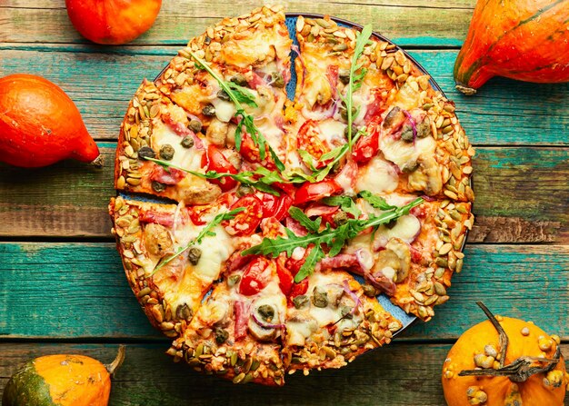 Pizza with salami, cheese, tomato on a pumpkin flatbread. Autumn recipe