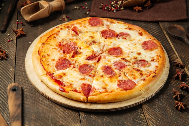 Pizza with salami and cheese on the wooden table