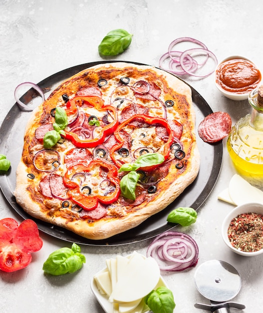 サラミ、タマネギ、コショウ、オリーブ、モッツァレラチーズ、バジルのピザ。自家製のホットペパロニのピザ。