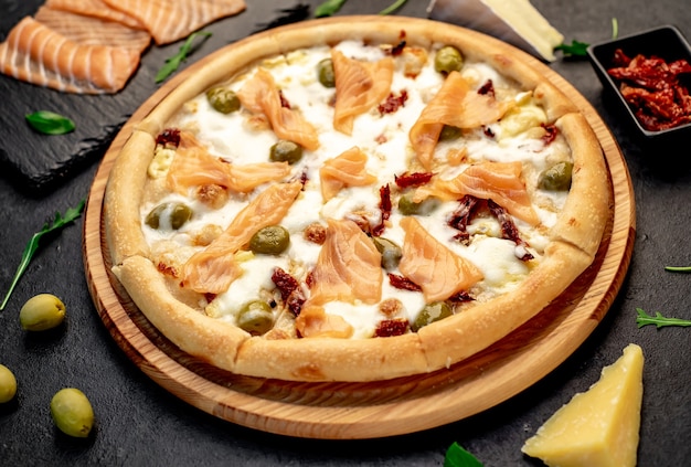 pizza with salmon cheese and olives on a stone background