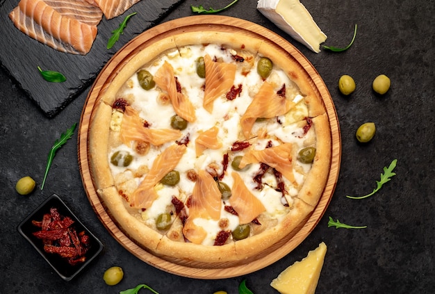 pizza with salmon cheese and olives on a stone background