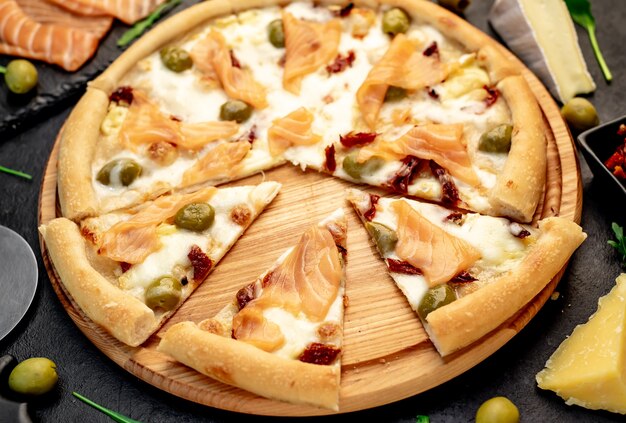 pizza with salmon cheese and olives on a stone background