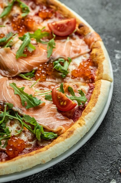 Pizza with salmon, red caviar, tomatoes and aragula. Traditional italian cuisine. vertical image. top view. place for text.