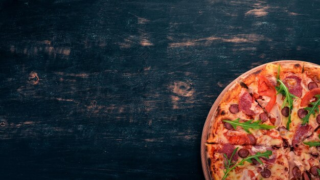 Pizza with sausage salami and mozzarella Top view On a wooden background Copy space