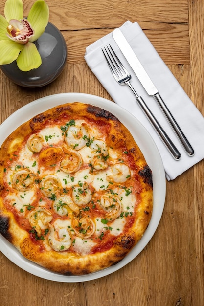 A pizza with shrimp on it next to a fork and knife.