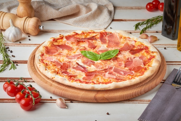 Pizza con fette, salsa ed erbe aromatiche, in legno bianco