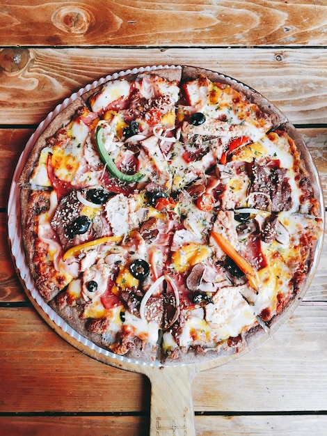 Pizza with tomato cheese capsicum onion on a wooden base