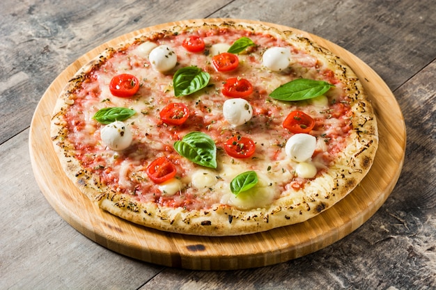 Pizza with tomatoes, cheese and basil on wooden table