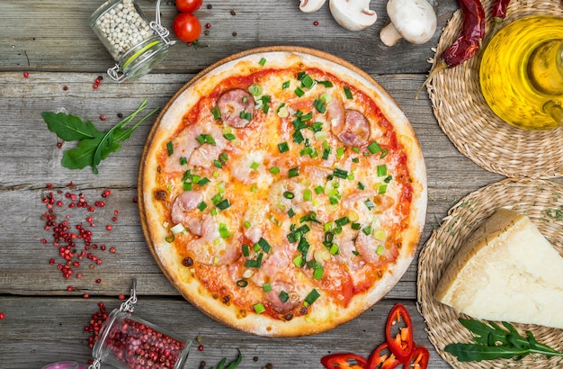 토마토, 모짜렐라 치즈, 블랙 올리브, 바질 피자. 나무 피자 보드에 맛있는 이탈리아 피자.