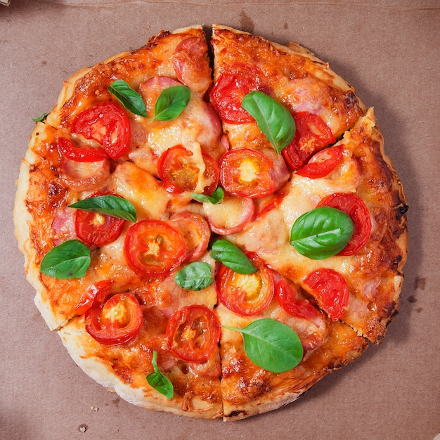 Pizza with tomatoes, sausages and cheese in a cardboard box