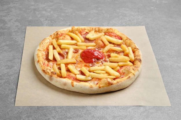 Pizza with various sausages and french fries on parchment paper