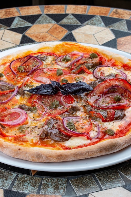 Pizza with veal tenderloin pepper and sweet onion rings On the stone table