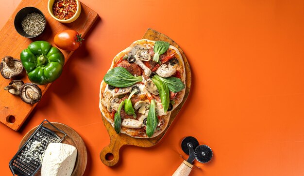 Pizza with vegetables, chicken, mashroom, ham and olives isolated on wooden board flat lay