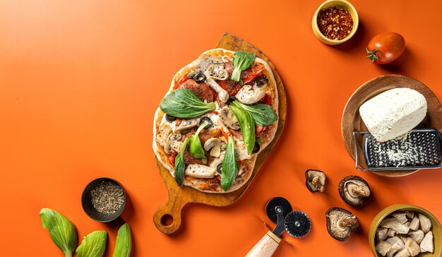 Pizza with vegetables, chicken, mashroom, ham and olives isolated on wooden board flat lay