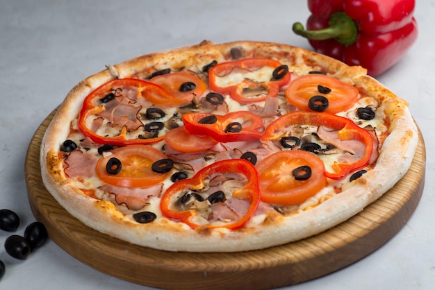 Pizza with vegetables and meat on a light background