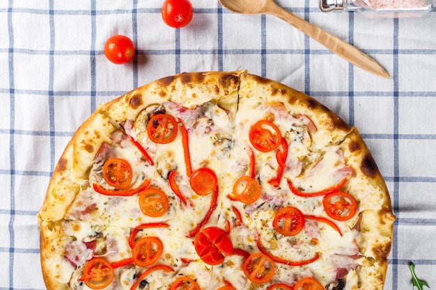 a pizza with a wooden spoon and a wooden spoon on a checkered table cloth.