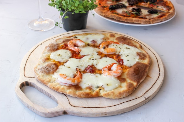 Pizza on a wooden board with mozzarella, mini arugula.