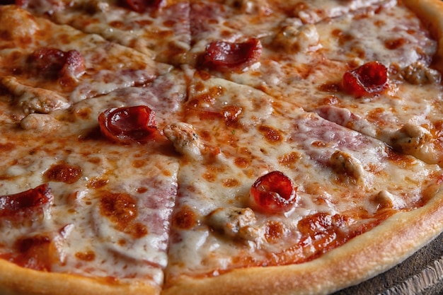 Photo pizza on a wooden board with pepper onions chicken cheese and tomatoes on a black backgroundpartially photographed