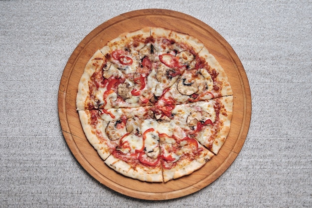 Pizza on wooden plank over gray background