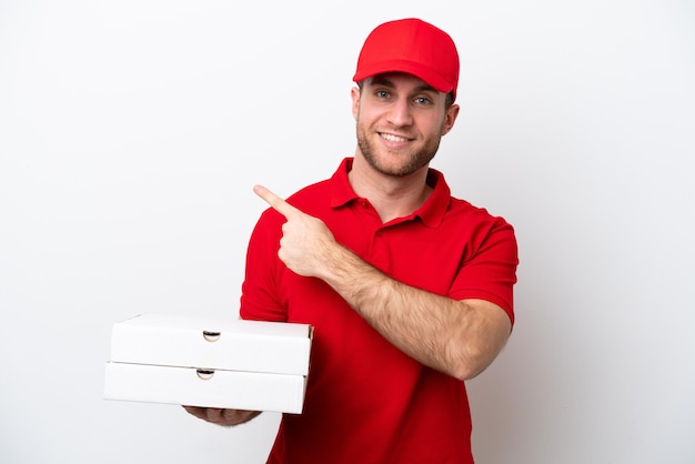 Pizzabezorger blanke man met werkuniform oppakken van pizzadozen geïsoleerd op een witte achtergrond wijzend naar de zijkant om een product te presenteren