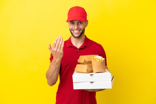 Pizzabezorger die pizzadozen en hamburgers ophaalt over een geïsoleerde achtergrond die uitnodigt om met de hand te komen. Blij dat je gekomen bent
