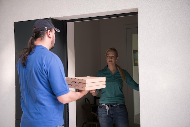 Pizzabezorger die pizzadozen geeft aan lachende jonge vrouw