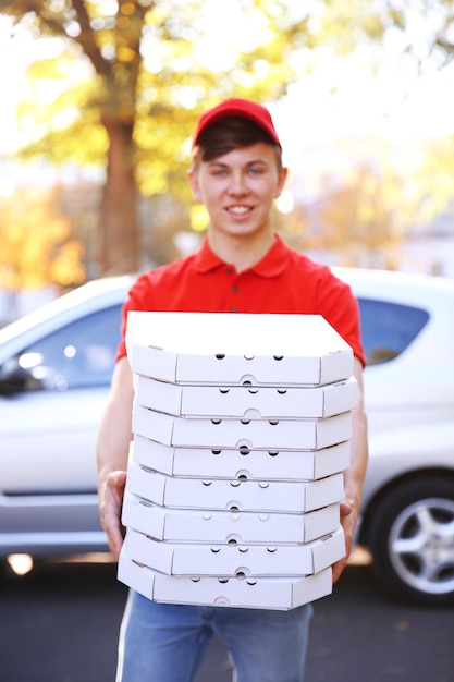 Foto pizzabezorger met dozen met pizza in de buurt van auto