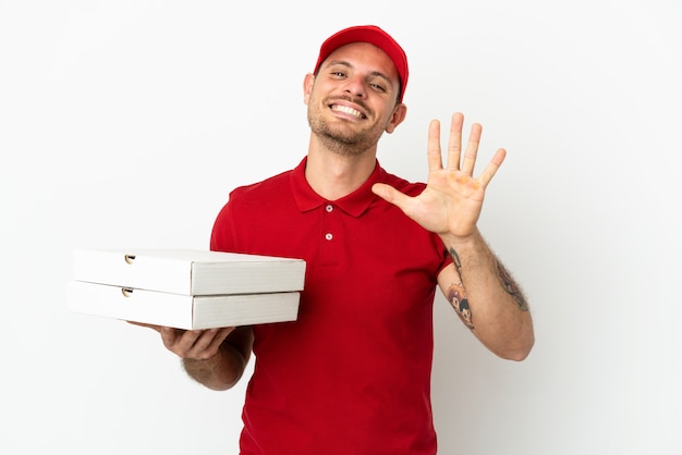 Pizzabezorger met werkuniform die pizzadozen ophaalt over geïsoleerde witte muur die vijf met vingers telt count