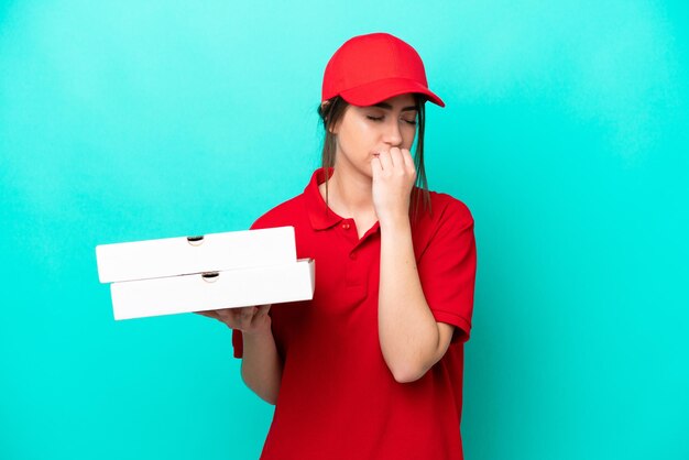 Pizzabezorger met werkuniform die pizzadozen oppakt die op blauwe achtergrond zijn geïsoleerd en twijfels heeft