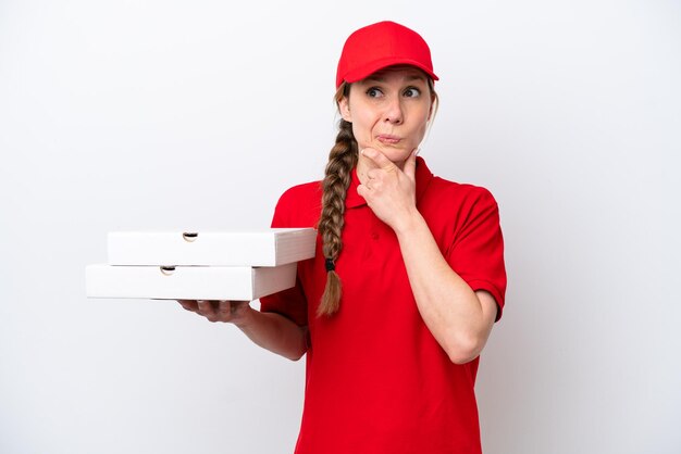 Pizzabezorger met werkuniform oppakken van pizzadozen geïsoleerd op een witte achtergrond met twijfels en denken