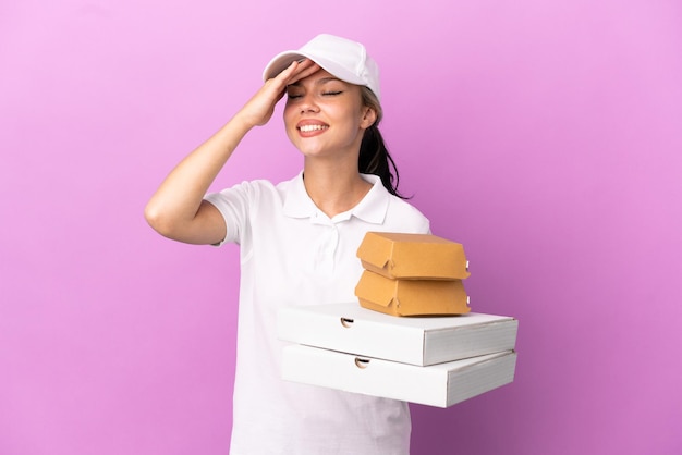 Pizzabezorger Russisch meisje met werkuniform die pizzadozen en hamburgers oppakt die op paarse achtergrond zijn geïsoleerd, heeft iets gerealiseerd en heeft de oplossing bedacht