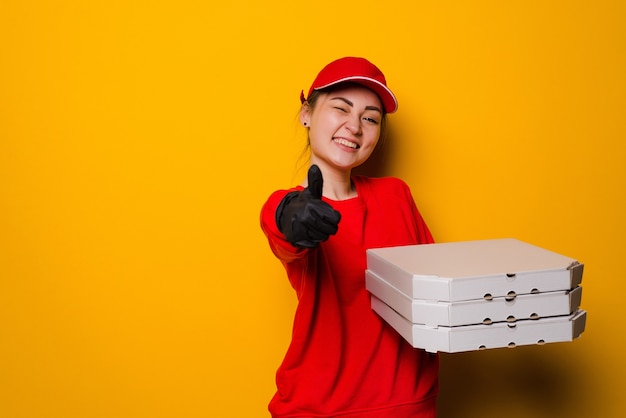 Pizzabezorger vrouw met drie dozen geïsoleerd op gele muur