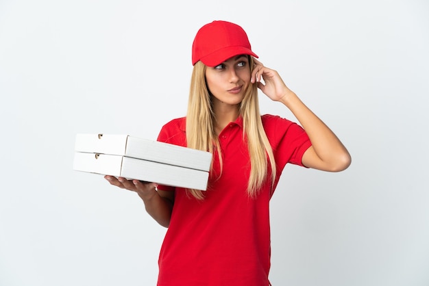 Pizzabezorger vrouw met een pizza geïsoleerd op een witte muur twijfels en denken