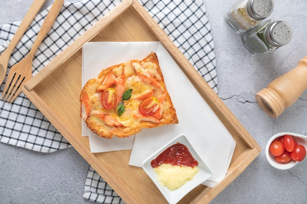 Pizzabrood belegd met garnalen krabsticks tomaten kaas in een houten dienblad