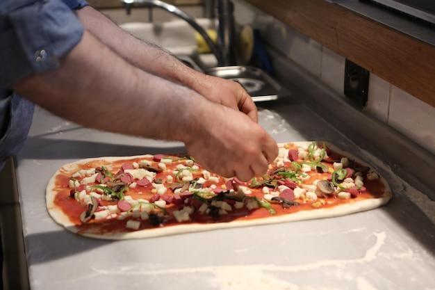 Pizzachef zet saus op basis in een commerciële keuken