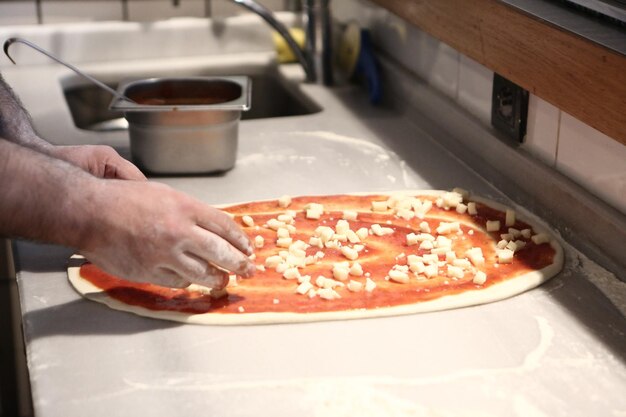 Pizzachef zet saus op basis in een commerciële keuken