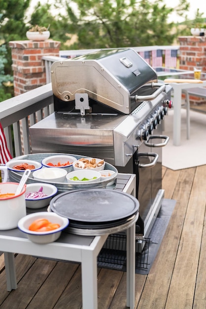 Pizzadeeg en ingrediënten voor het grillen van pizza op een buitengasgrill.