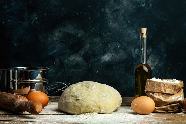 Pizzadeeg het koken in de huiskeuken. Zelfgemaakt deeg voor brood, pizza, gebak en broodjes. Deeg ingrediënten op een houten rustieke achtergrond