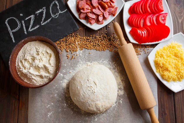 Pizzadeeg met ingrediënten op hout