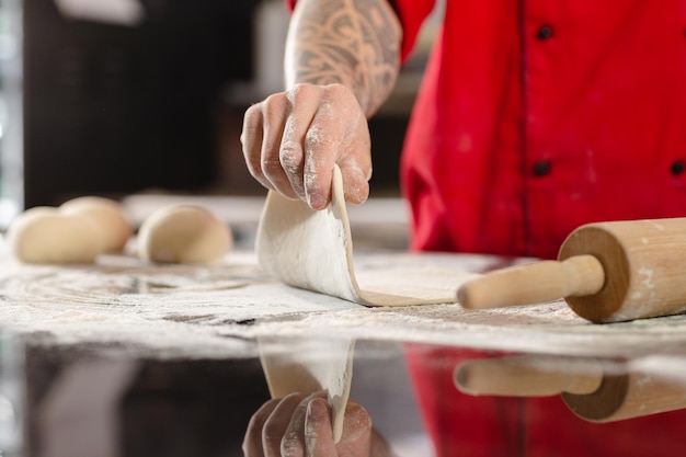 Pizzaiolo prepares pizza in the kitchen the chef prepares the dough