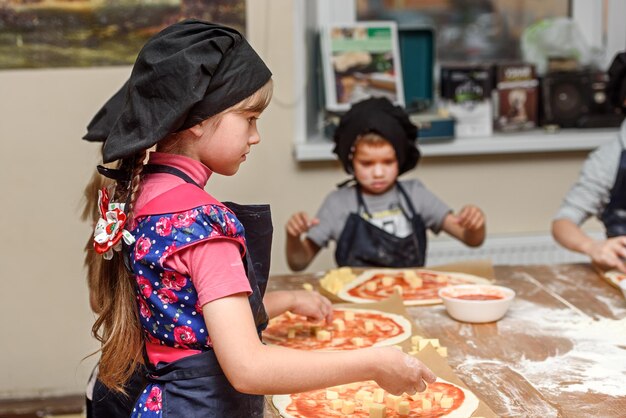 Pizzakinderen en het concept van kokende kinderen maken pizza