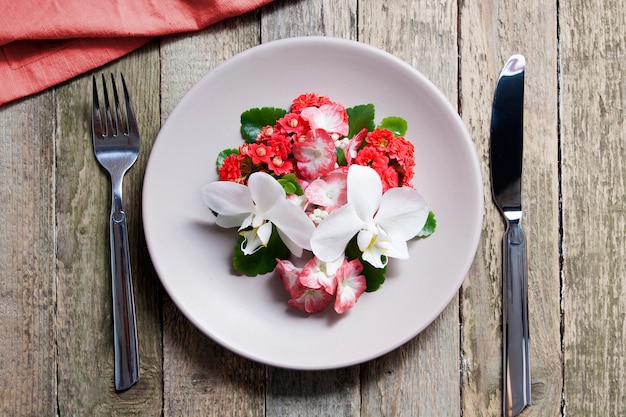 Plaat met bloemen en bestek op een houten tafel