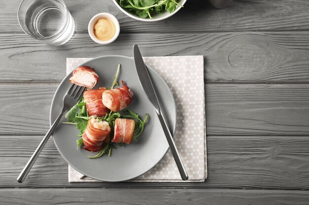 Plaat met in spek gewikkelde kipnuggets op tafel