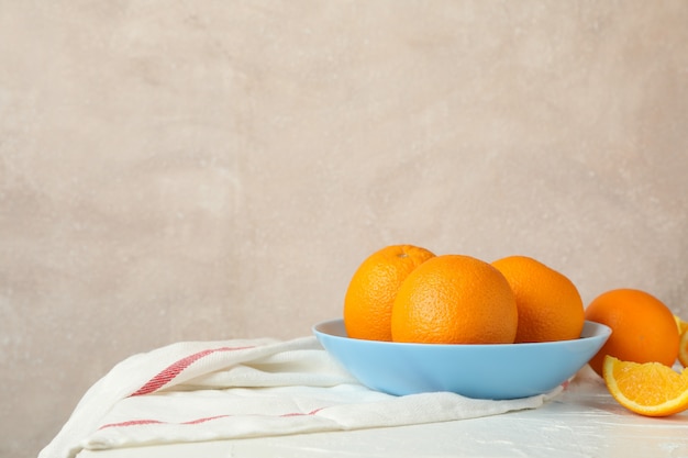 Plaat met sinaasappelen en keuken handdoek op witte tafel tegen lichte achtergrond, ruimte voor tekst