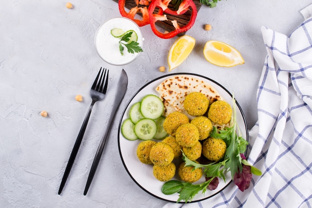 Plaat van gebakken falafel met pitabroodje, saus en slablaadjes