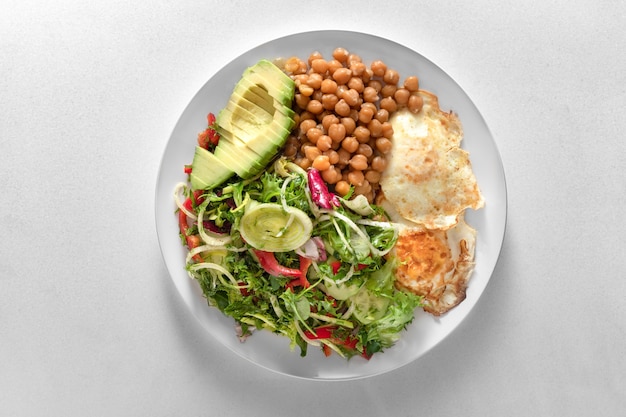 Plaat van gezonde voeding Kipfilet, salade, avocado en volkoren rijstepap. In een wit bord op een standaard van zwarte leisteen.