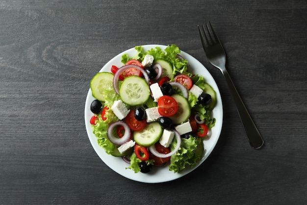 Plaat van Griekse salade en vork op donkere houten