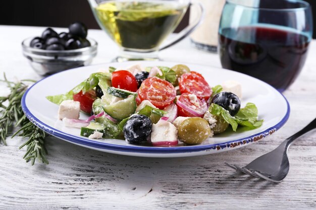 Foto plaat van griekse salade geserveerd met wijn en olijfolie op houten tafel op donkere achtergrond